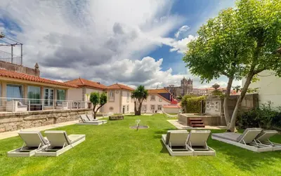 a yard with lounge chairs on the grass at Oca Flores Hotel Boutique in Porto