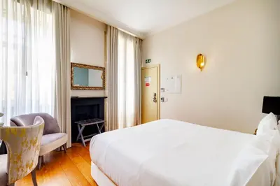 a hotel room with a white bed and a chair at Oca Flores Hotel Boutique in Porto