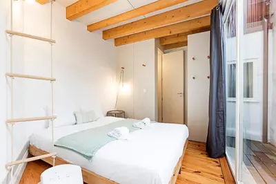 a bedroom with a white bed and wooden ceilings at Charming Retreat with Balcony in Porto
