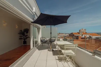 a balcony with a table and chairs and an umbrella at Porto Panoramic Views With Terrace by Vacationy in Porto