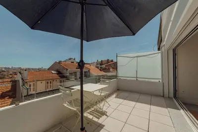 an umbrella on a balcony with a table and chairs at Porto Panoramic Views With Terrace by Vacationy in Porto