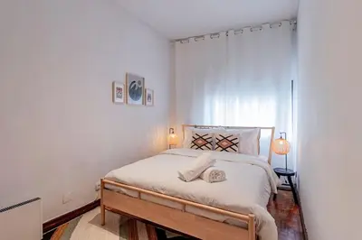 a bedroom with a large bed with white walls at Apartamento com terraço in Porto