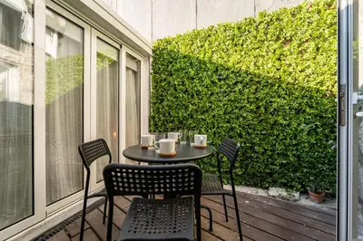 a table and chairs on a balcony with a green hedge at Oporto Nura Apartment Downtown in Porto