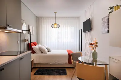 a bedroom with a bed and a table and a kitchen at C&P Bolhão Downtown Studio in Porto