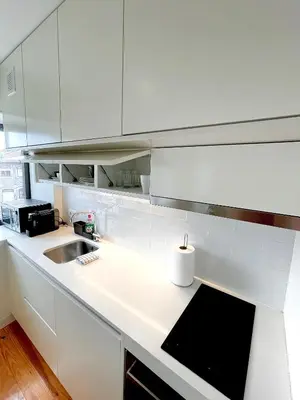 a kitchen with white cabinets and a sink at Cozy Studio in the Heart of Porto in Porto
