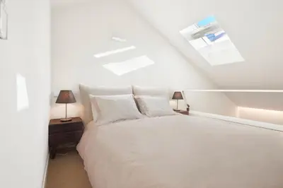 a white bedroom with a large bed with white pillows at Dux in Porto