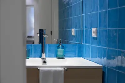 a blue tiled bathroom with a sink and a mirror at Dux in Porto