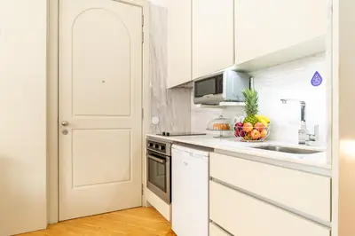 a kitchen with white cabinets and a bowl of fruit on the counter at Host Wise - Colourful Cozy Flat in Porto