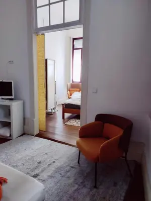 a living room with a chair and a bedroom at Central Stonehouse with terrace in Porto