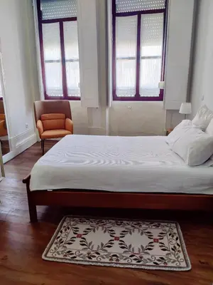 a bedroom with a large bed and a chair at Central Stonehouse with terrace in Porto