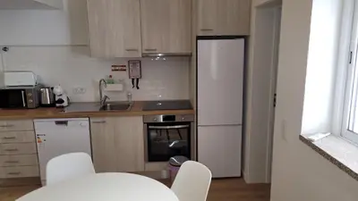 a kitchen with white appliances and a table and chairs at Guest House CR5 in Porto