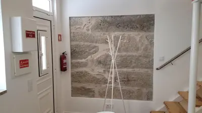 a stone wall in a room with a painting on the wall at Guest House CR5 in Porto