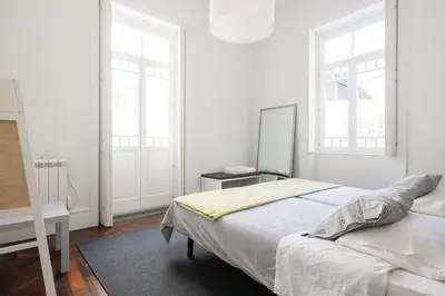 a white bedroom with a bed and two windows at Baixa24 · City Center Private Sun Deck Apartment in Porto