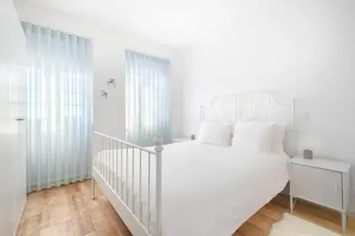 a white bedroom with a white bed with white pillows at Green Tiles House in Porto