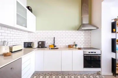 a white kitchen with white cabinets and appliances at Green Tiles House in Porto