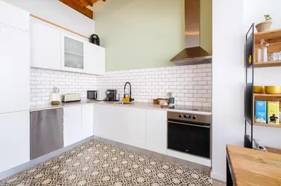 a kitchen with white cabinets and a tile floor at Green Tiles House in Porto