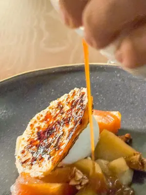 a person drizzling orange sauce on a plate with food at Palacete Severo in Porto
