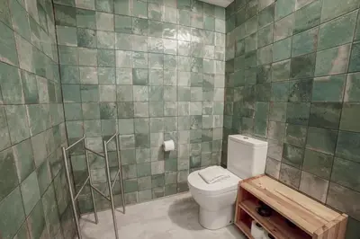 a bathroom with a toilet and a green tiled wall at Clerigos Loft by Hosty in Porto