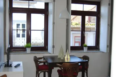 a dining room with a table and chairs and windows at Studios Cedofeita in Porto