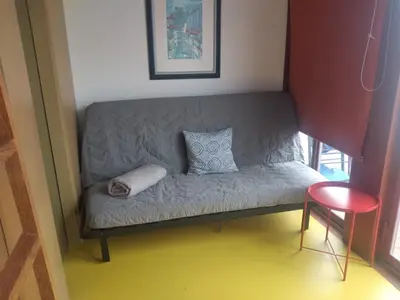 a small couch in a room with a red stool at Porto Studio in Porto