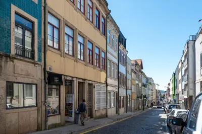 a man walking down a city street with buildings at Doispontozero Alegria Terracotta in Porto