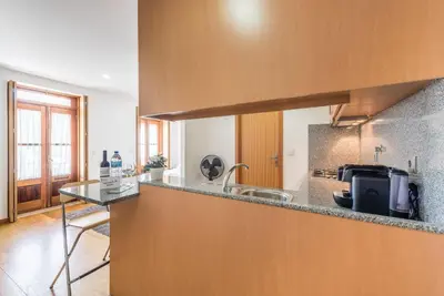 a kitchen with wooden cabinets and a counter with two chairs at GuestReady - Daisy boutique in Porto