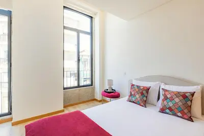 a bedroom with a bed and a large window at Duque de Saldanha Residences in Porto