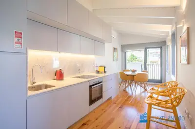 a kitchen with white cabinets and a table and chairs at Boavista Central Garden & Terrace in Porto