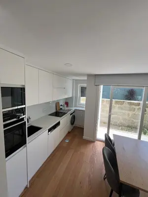 a kitchen with white cabinets and a table with chairs at Cozy Retreat - Modern T1 in Porto