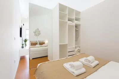 a white bedroom with two towels on a bed at GuestReady - Blueberry Pie in the Balcony in Porto