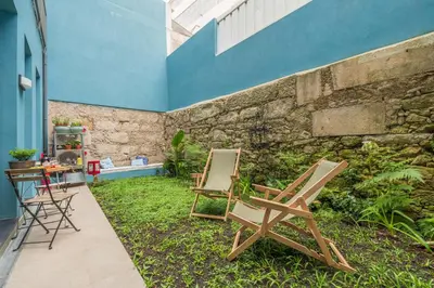two chairs sitting on the grass next to a building at Host Wise - Stylish Urban Flat with Terrace in Porto