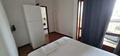 a room with a white bed and a refrigerator at Leote in Porto