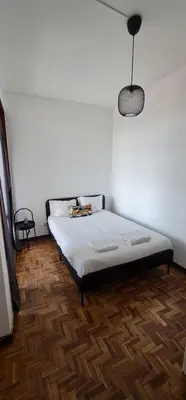 a bed in a room with a white wall at Leote in Porto