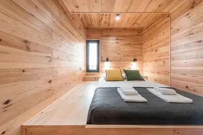 a bedroom with a large bed in a wooden wall at GuestReady - Contemporary cabin in Santos Pousada in Porto