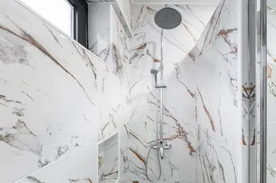 a bathroom with a shower with white marble walls at GuestReady - Contemporary cabin in Santos Pousada in Porto