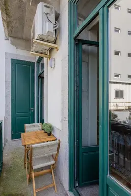a table and chairs next to a building with green doors at Liiiving in Porto - Bolhao Garden Apartment in Porto