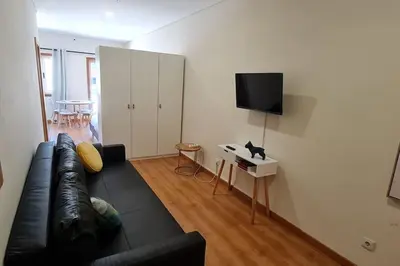 a living room with a black leather couch and a television at Tomás FLAT 4F in Porto