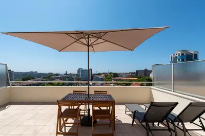 a balcony with two chairs and a table on a roof at DoisPontoZero Júlio Dinis Gold in Porto