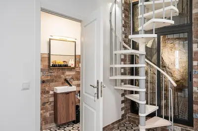 a bathroom with a spiral staircase next to a brick wall at GuestReady - Serene Hideout in Downtown in Porto