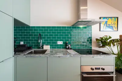 a kitchen with a sink and a green tile wall at Aires Gouveia Penthouse in Porto