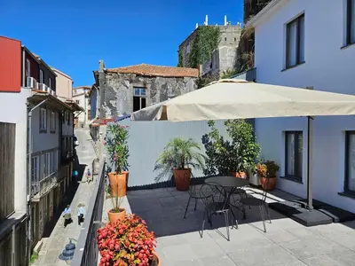 a patio with an umbrella and a table and flowers at Authentic Porto Village in Porto