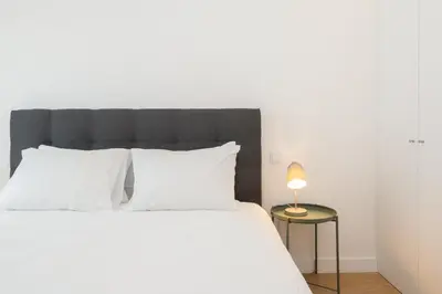 a bed with white pillows and a lamp on a table at GuestReady - Modern 2-Bedroom Apt in Cedofeita in Porto