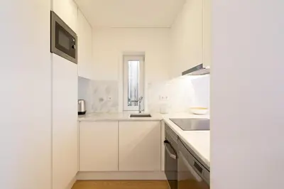 a white kitchen with white cabinets and a sink at GuestReady - Modern 2-Bedroom Apt in Cedofeita in Porto