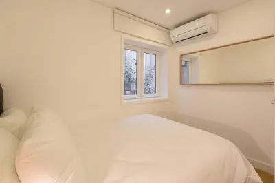 a white bedroom with a bed and a mirror at GuestReady - Modern 2-Bedroom Apt in Cedofeita in Porto