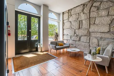 a bedroom with a stone wall and a table and chairs at GuestReady - Porto de Rio Residences in Porto