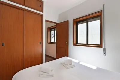 a bedroom with a white bed and a window at Bessa - Casinha Típica do Porto com dois quartos in Porto