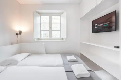a white bedroom with two beds and a flat screen tv at GuestReady - Riverview Douro Balcony in Vila Nova de Gaia