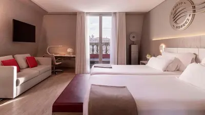 a hotel room with two beds and a couch at NH Collection Porto Batalha in Porto