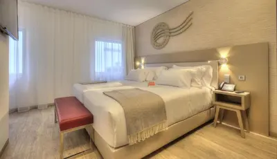 a hotel room with a large bed and a window at NH Collection Porto Batalha in Porto