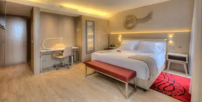 a bedroom with a large white bed and a desk at NH Collection Porto Batalha in Porto